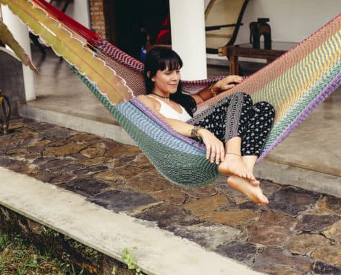 Girl sitting in colourful hammock in garden